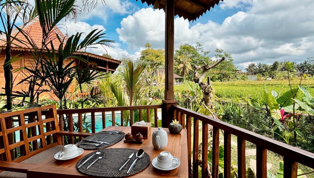 乌布Jagadhita Villas Ubud Bali的阳台上配有带板子和银器的木桌