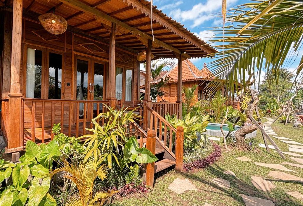 乌布Jagadhita Villas Ubud Bali的一座带门廊和一些植物的木屋
