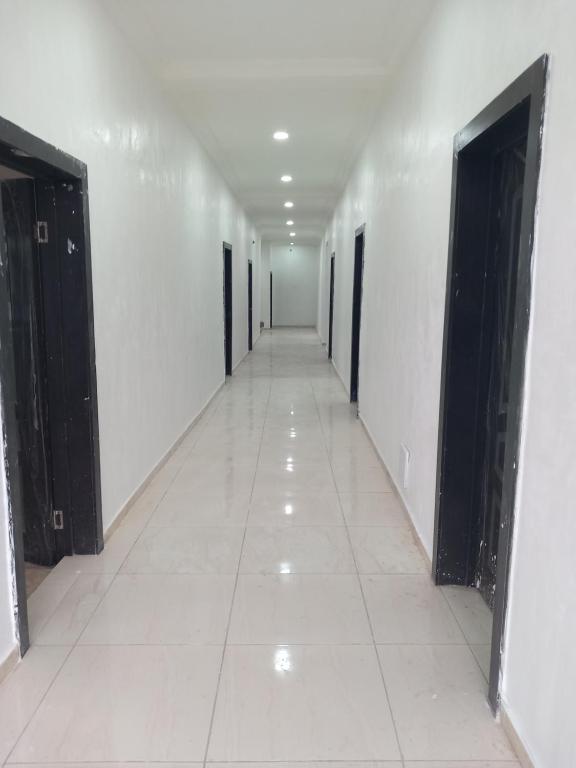 贝宁城Tovia Hotel and Suite Limited的空的走廊,有门,铺着瓷砖地板