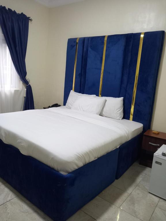 贝宁城Tovia Hotel and Suite Limited的一张带蓝色床头板的睡床