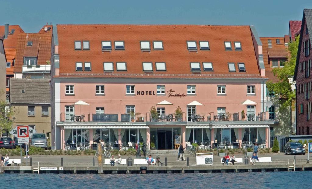 瓦伦Hotel Am Yachthafen的水体旁的一座粉红色大建筑