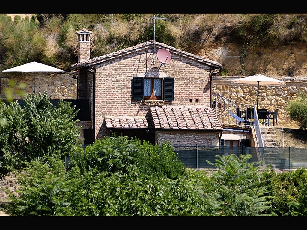 蒙特普齐亚诺La Casina Toscana的砖屋,设有窗户、桌子和雨伞