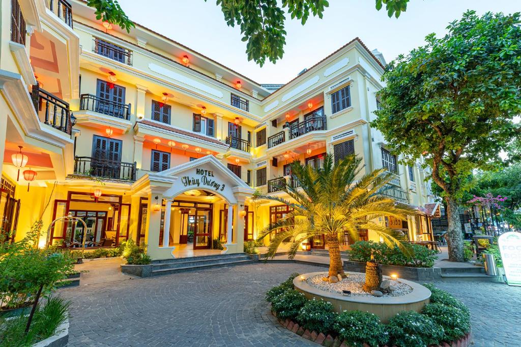 会安THUY DUONG 3 Boutique Hotel & Spa的前面有树木的白色大建筑