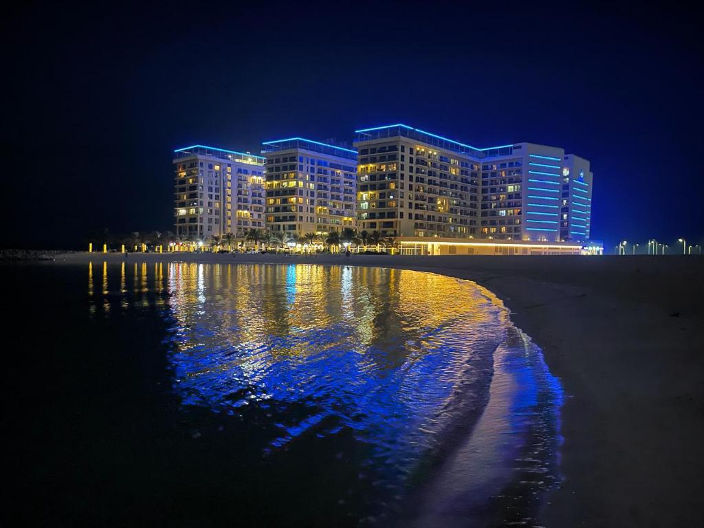 拉斯阿尔卡麦Infinity Blue - Studio on Al Marjan Island with a private beach的夜间在水中反射的酒店