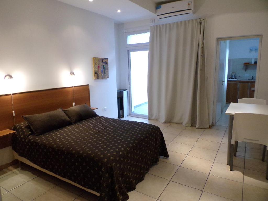 布兰卡港Apartamentos Güemes - Monoambientes的一间卧室配有一张床、一张桌子和一个窗户。