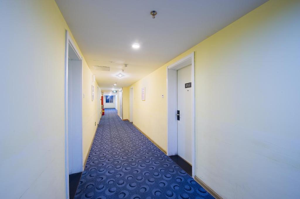 广州7天连锁酒店广州黄埔东区时代城店的办公室的走廊,有白色的墙壁和蓝色的地毯