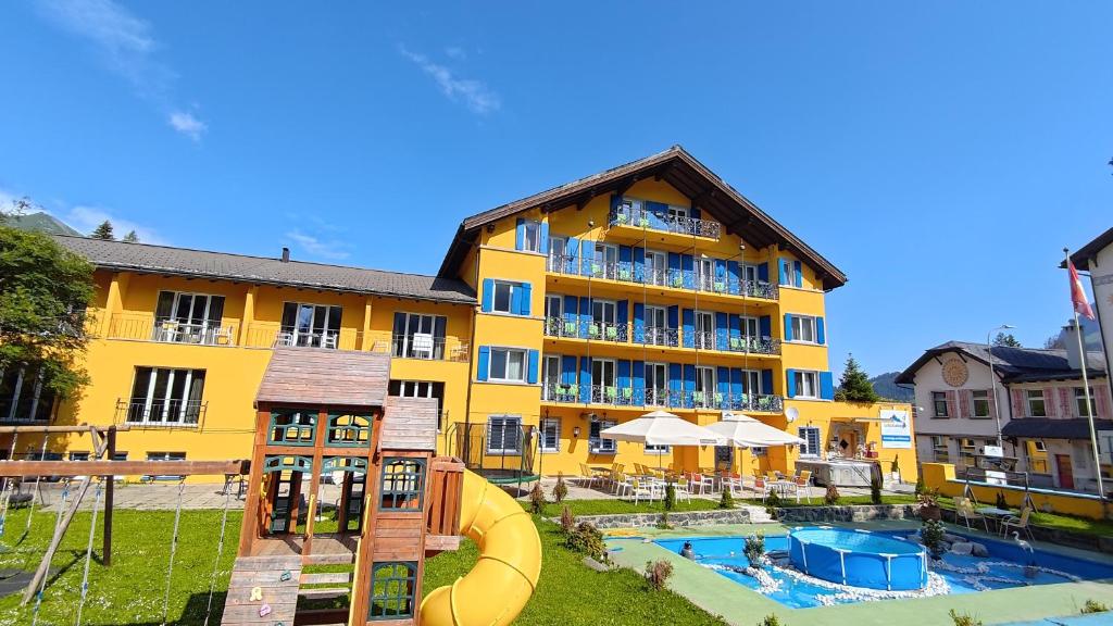 帕尔潘Grischalodge das Hotel mit Bergblick seit 1929 - Bitte beachten Sie beim buchen auf die Zimmerkategorie的大型黄色酒店,设有滑梯和游乐场