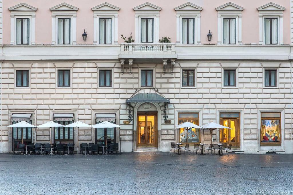 罗马阿尔伯格戴尔萨纳托酒店的前面有桌子和伞的建筑