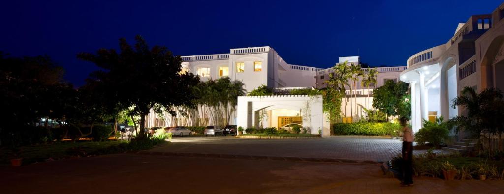 NāmakkalNala Hotels的一座白色的大房子,晚上灯亮