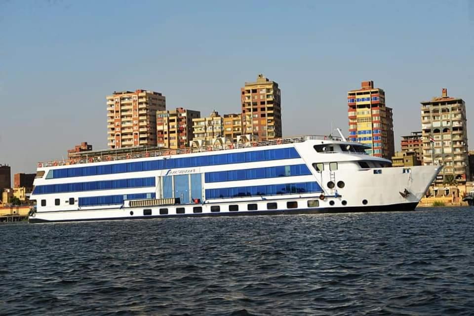 卢克索Cleopatra Nile 5 Star Trek Cruise every Friday from Aswan for 3 Nights Every Monday from Luxor 4 Nights的一艘大船在水中,船底有建筑物