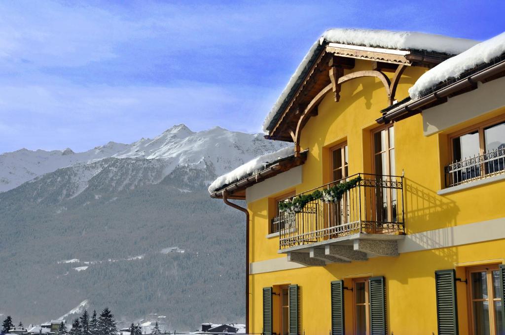 博尔米奥穆布雷赛托雷丽里特酒店的一座黄色的建筑,底下是雪覆盖的山