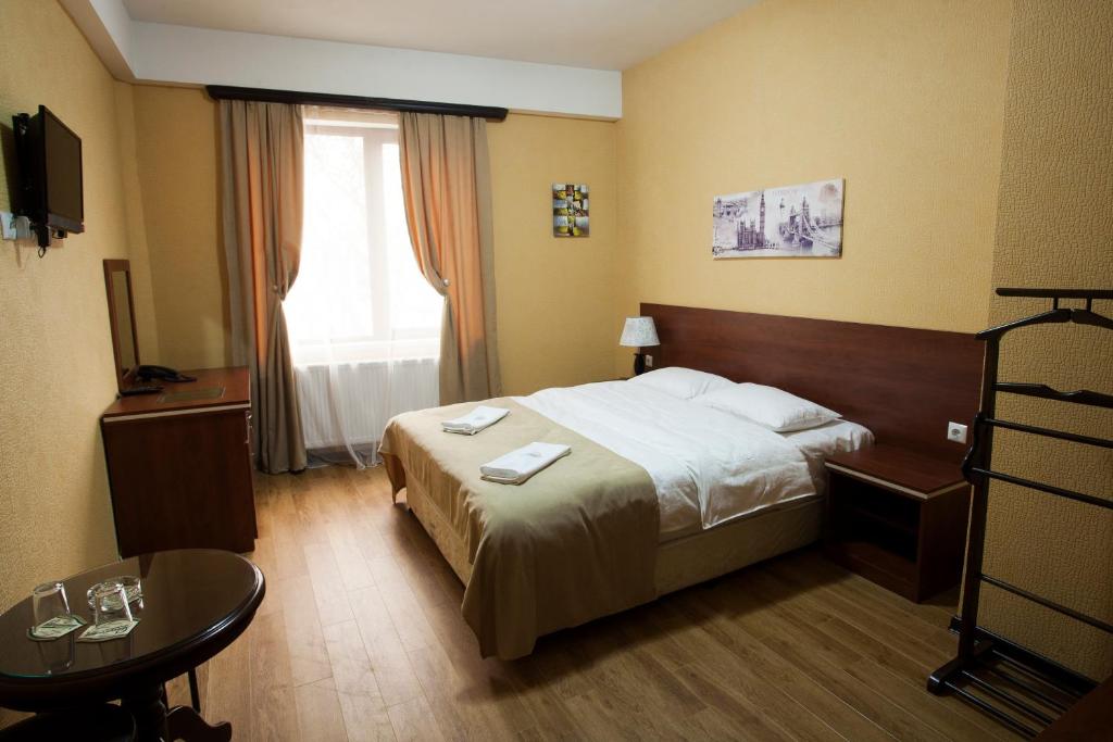 第比利斯Lords Hotel的酒店客房配有一张床铺和一张桌子。