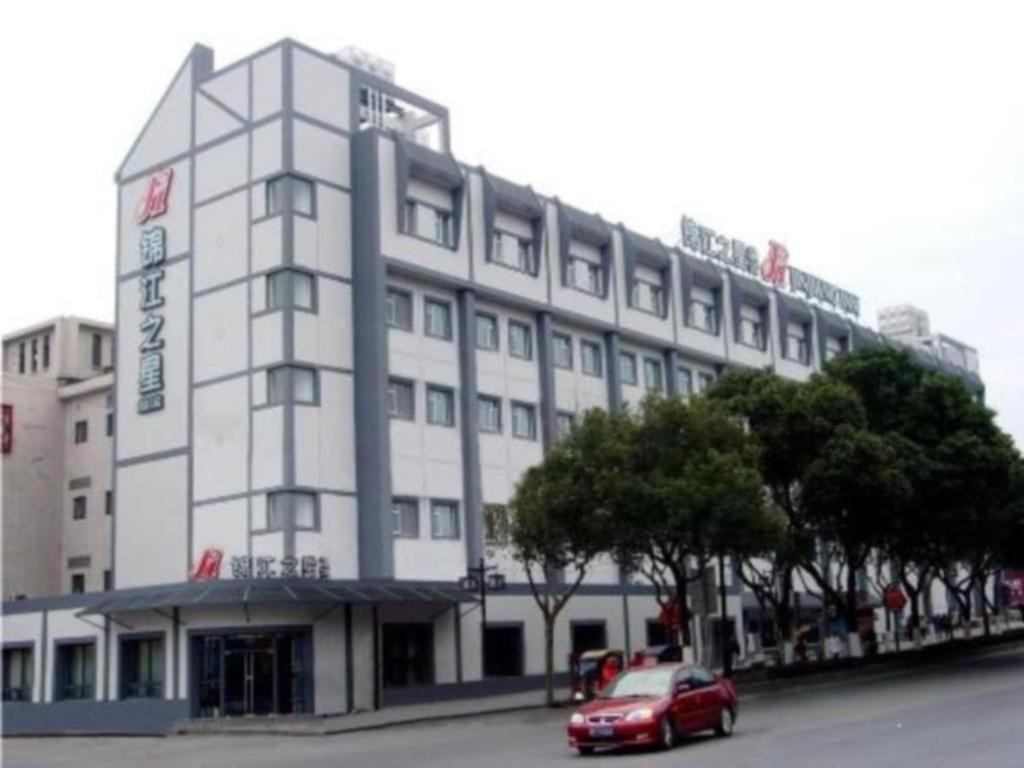 苏州Jinjiang Inn Suzhou Tuanjieqiao Metro Station的停在大楼前的红色汽车