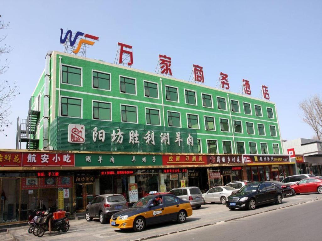 北京Beijing Wanjia Traders Hotel的一条绿色的建筑,在街上写着中国文字