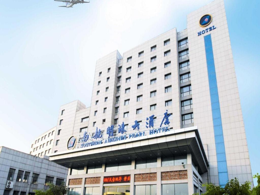 大连Dalian Southern Airline Pearl Hotel的飞机飞越它的建筑物