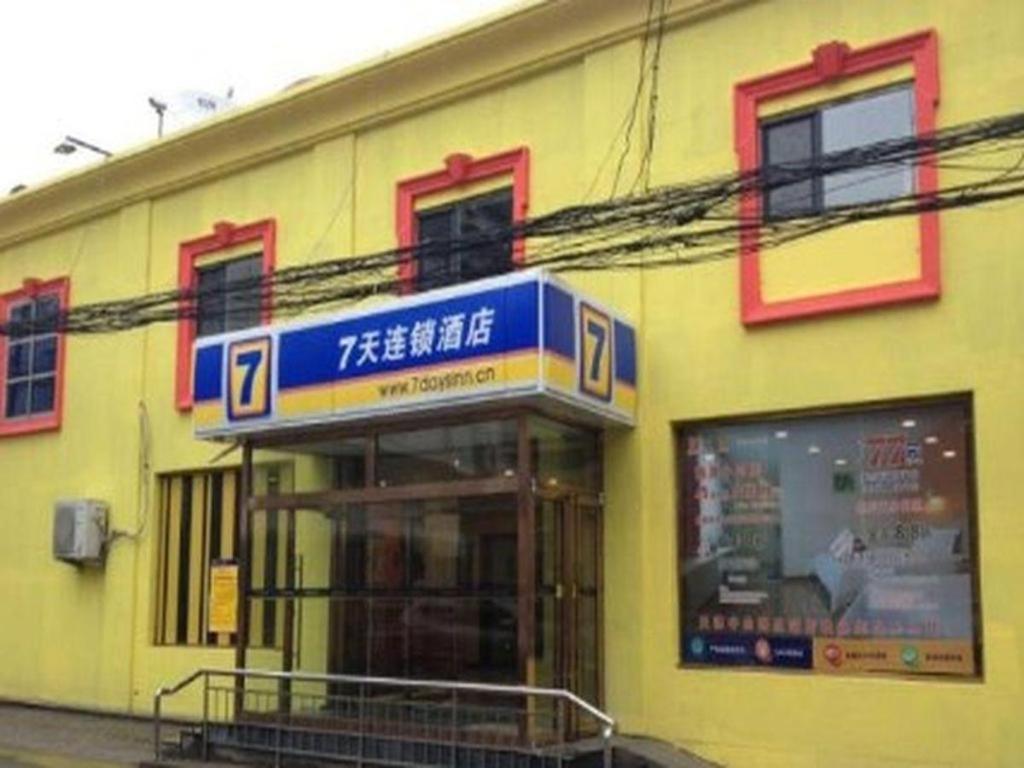 天津7 Days Inn Tianjin Zhongshan Road North Station的黄色的建筑,旁边标有标志