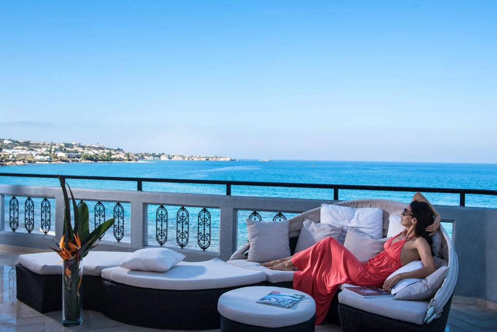 赫索尼索斯索尼娅别墅酒店的坐在阳台上沙发上的红色衣服上的女人
