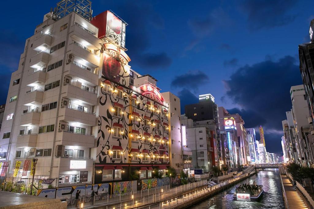 大阪Rose Lips Shinsaibashi ローズリップス心斎橋的城市的河上,晚上的建筑物