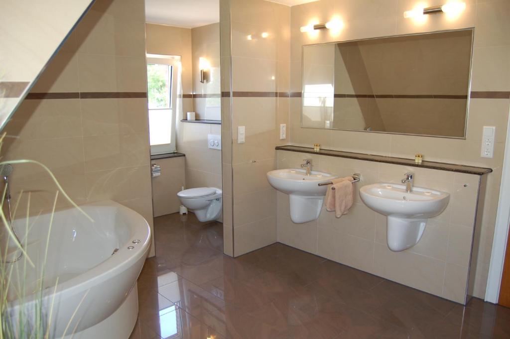 库克斯港Strandhaus Deichvoigt的一间带两个盥洗盆、浴缸和卫生间的浴室