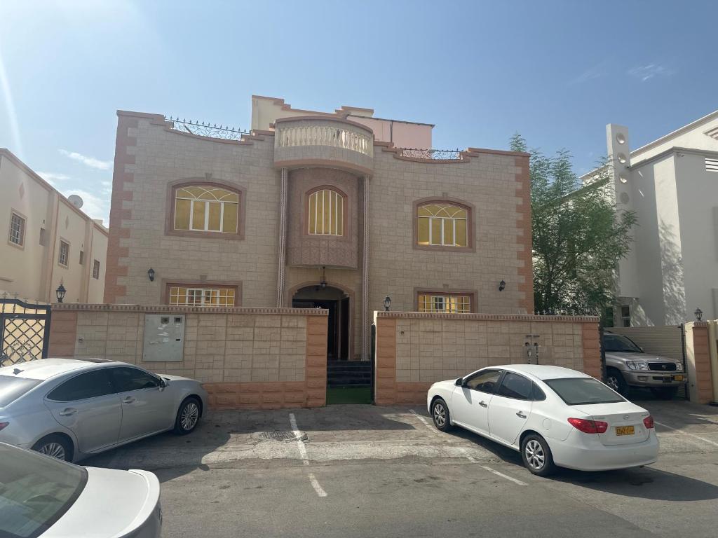 Al Khawḑغرف إيجار يومي Daily rent rooms的两辆汽车停在大楼前的停车场