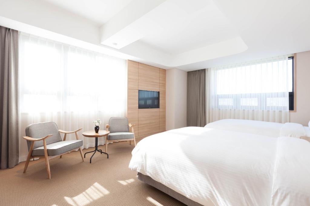首尔东大门阿酷酒店的一间卧室配有一张床、两把椅子和一张桌子