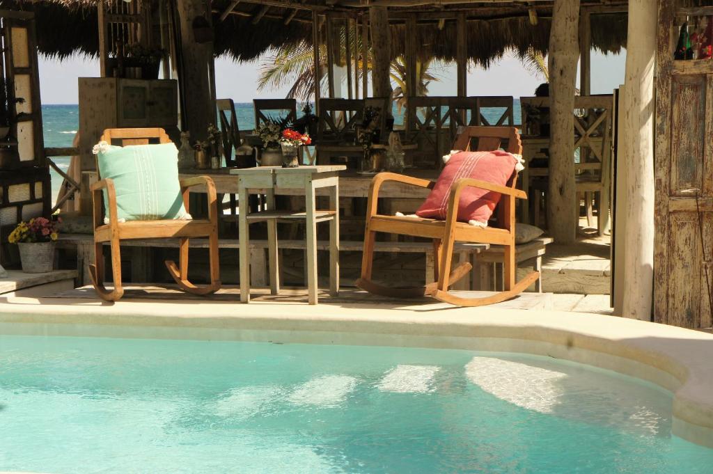 图卢姆波萨达蓬彼德拉海滩酒店的游泳池畔的两把椅子和一张桌子