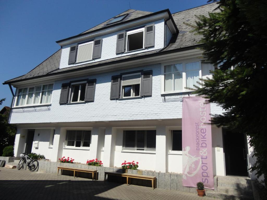 科齐扎尔滕Black Forest Bike Hostel的前面有粉红色横幅的白色建筑