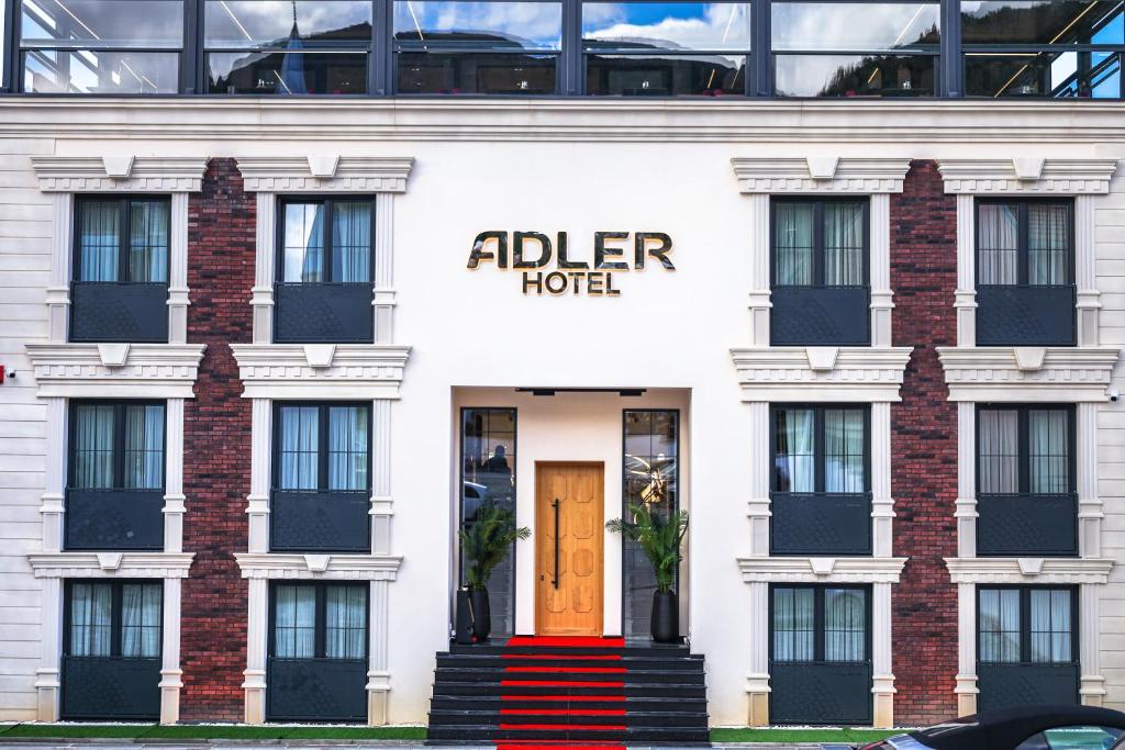 普里兹伦Adler Hotel的一座白色的建筑,设有红色的门,酒店更坚硬