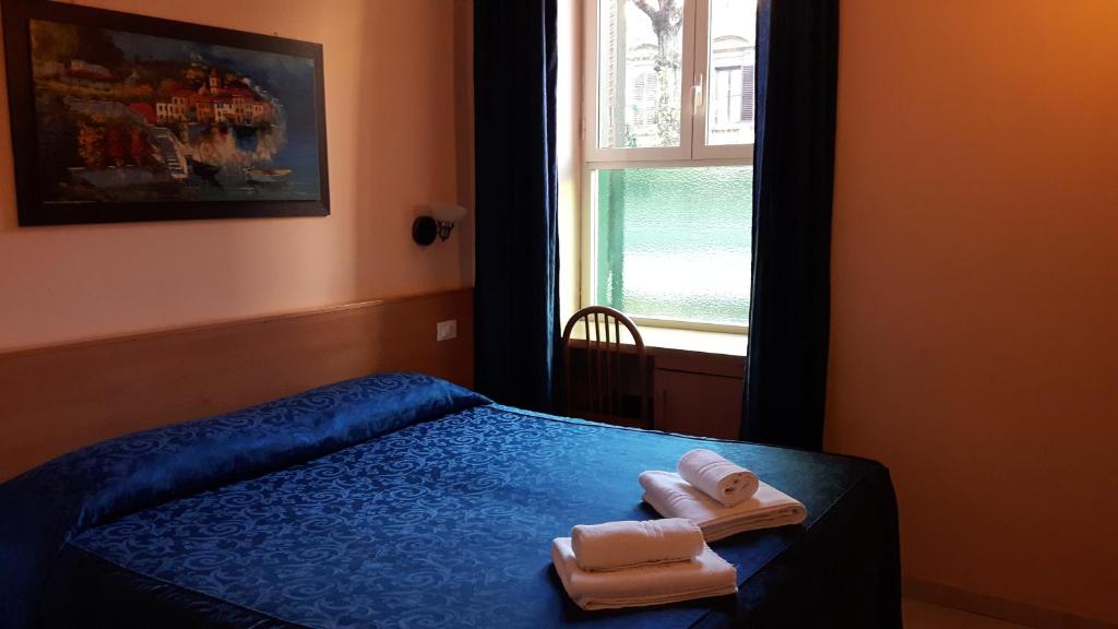 罗马帕尔玛酒店的一间卧室配有带毛巾的床和窗户。
