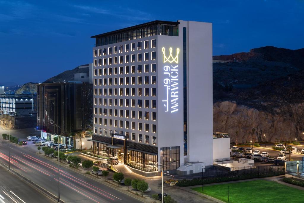 Al ‘AbābīdWarwick Al Taif Hotel的一座高大的建筑,旁边有一个标志