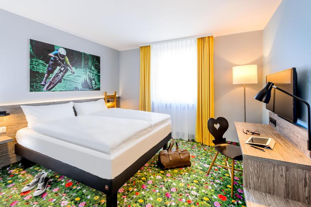 考夫博伊伦Felix Hotel Kaufbeuren的酒店客房配有一张床、一张书桌和一台电视。