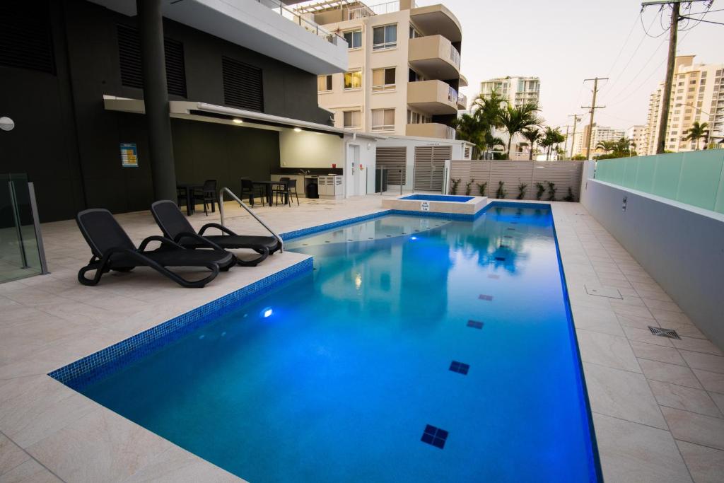 玛志洛木棉活力公寓式酒店的大楼内一个带两把椅子的游泳池