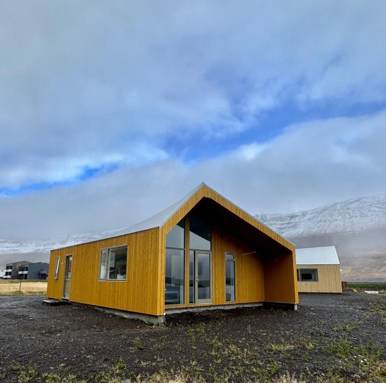 SuðureyriFisk Club Cottages - Captain's house的坐在田野顶上的一个小黄房子