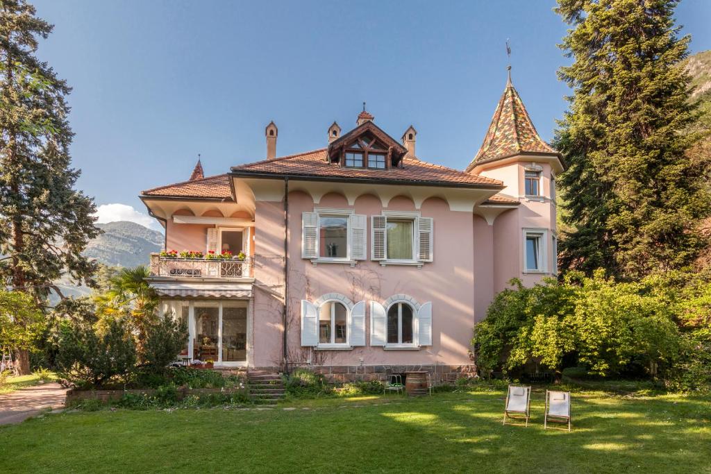 博尔扎诺安妮塔客房别墅旅馆的一座粉红色的房子,在院子的顶部有一座塔