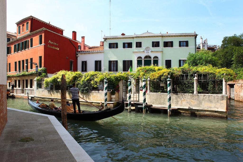 威尼斯佩西恩那阿卡德米亚玛拉维吉别墅酒店的缆车停靠在建筑物旁边的运河上