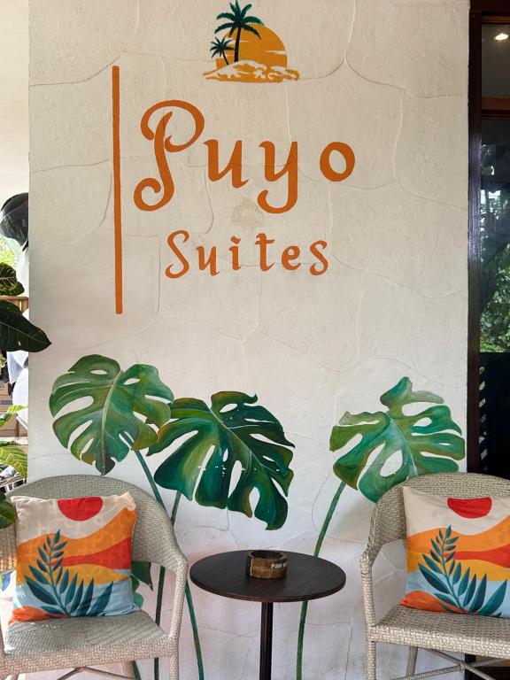 卢纳将军城Puyo Suites Homestay的皮尼翁冲浪店的标志,上面有两把椅子和一张桌子