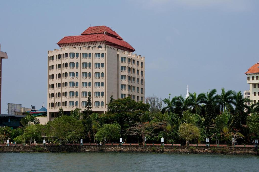 科钦Vivanta Ernakulam, Marine Drive的一条大白色的建筑,有红色的屋顶,毗邻一条河流