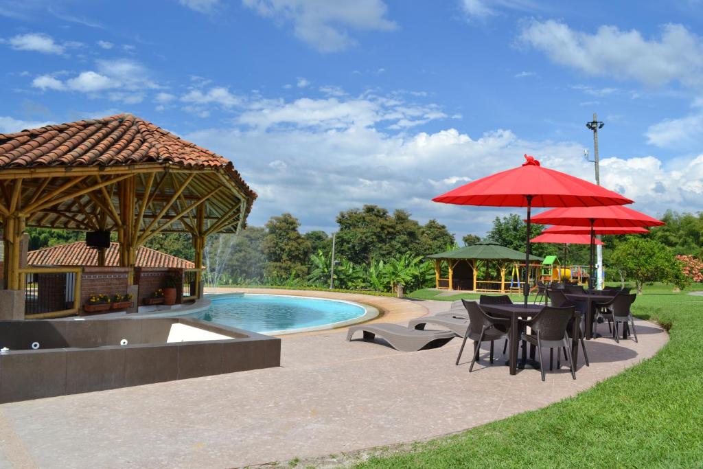 蒙特内哥罗Hotel Campestre Montecarlo的游泳池旁带桌子和遮阳伞的天井