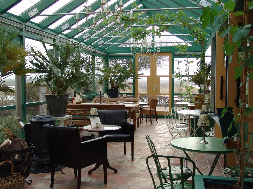 莱利斯塔德Hajé Hotel Restaurant de Lepelaar的一个带桌椅和植物的温室