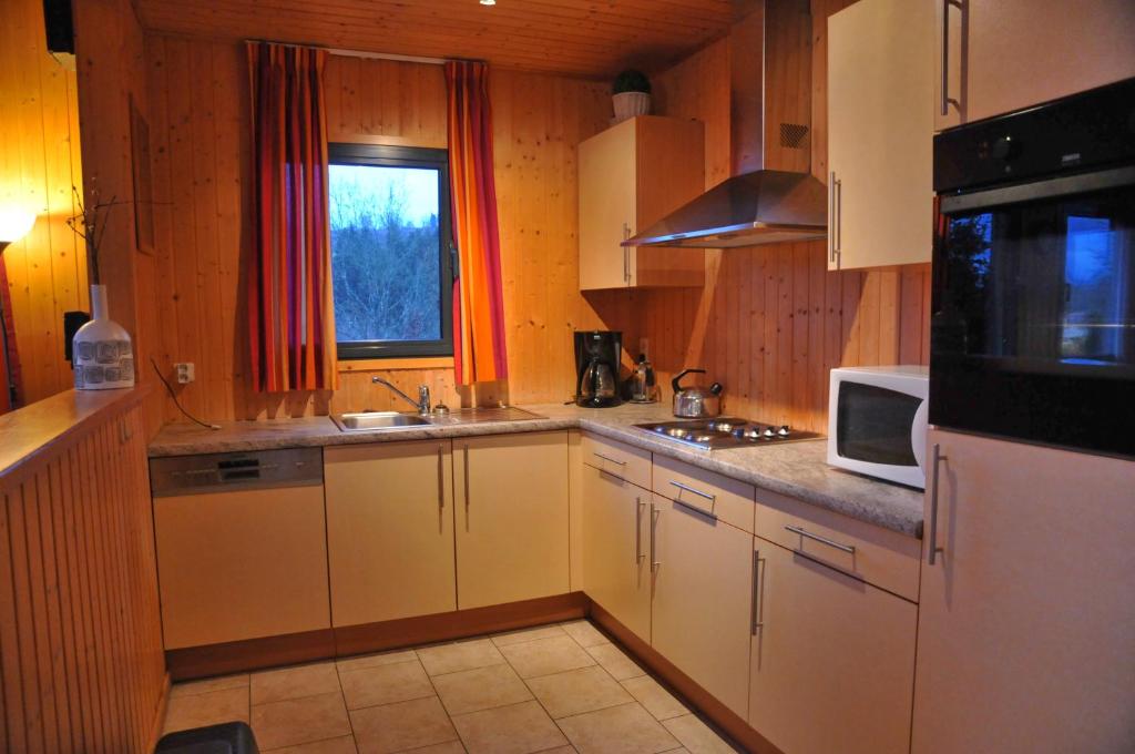 胡法利兹Jardins de L'Ourthe 8的厨房配有白色橱柜和微波炉