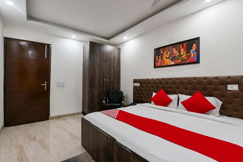 新德里Hotel O Premium Rooms Chhatarpur的一间卧室配有一张带红色枕头的大床