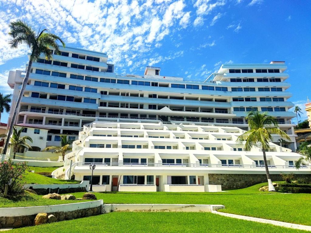 阿卡普尔科Hotel Aristos Acapulco的一座白色的大建筑,前面有棕榈树