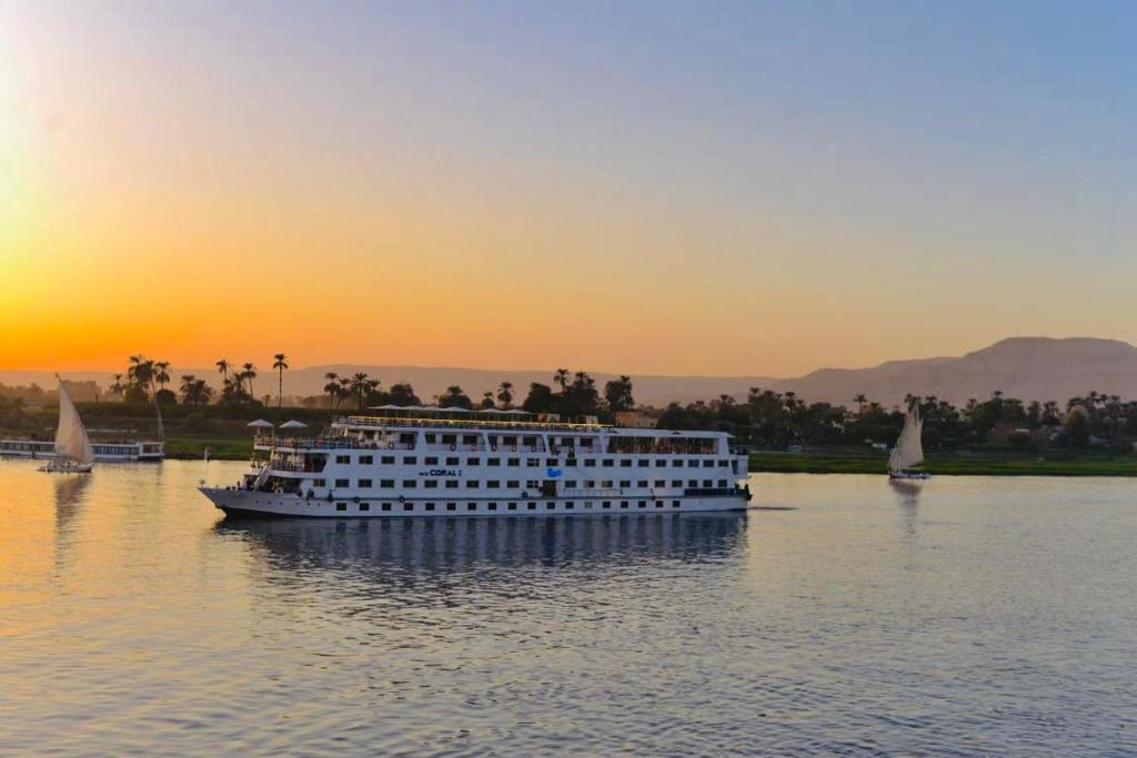 卢克索Luxor Aswan Coral 2 Nile Cruise every Saturday from Luxor 4 nights & every Wednesday from Aswan 3 nights的日落时分在水面上的游轮