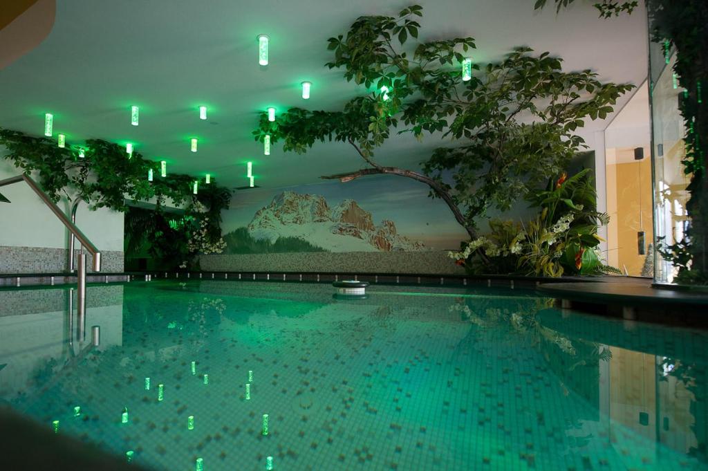 维哥迪法萨Family & Wellness Hotel Fontana的一座带绿灯的游泳池
