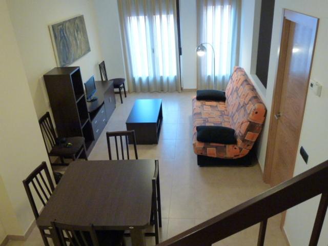 特鲁埃尔普尔塔穆来拉公寓酒店的客厅配有桌子、沙发和椅子