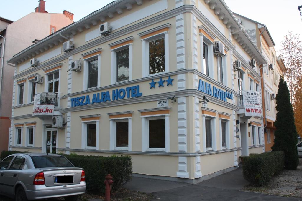 塞格德蒂萨阿尔法酒店的白色的建筑,前面有标志