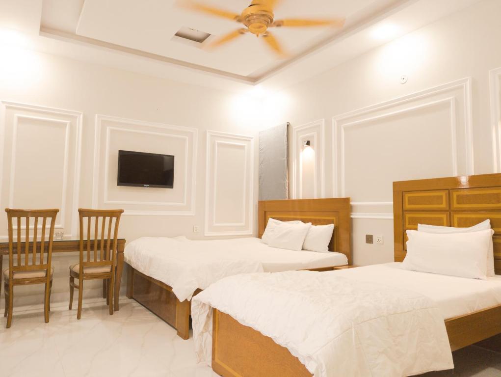 卡拉奇Stay Inn Hotel Rooms Karachi - Gulshan - Agha Khan Hospital - Airport的配有两张床铺的房间,配有两把椅子和电视