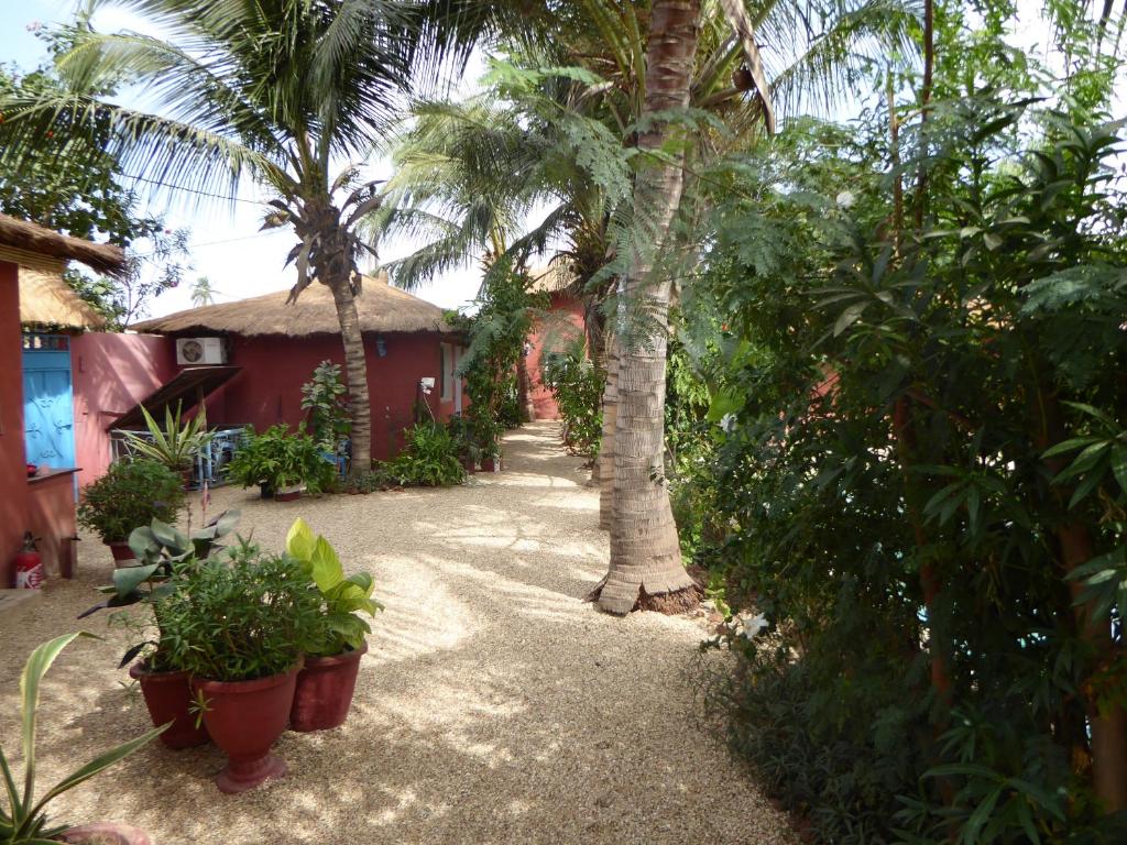 Joal-FadioutHôtel Joal Lodge的一座花园,花园内种有棕榈树和植物,位于一座房子前面