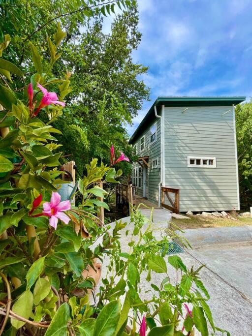 奥斯汀Cozy Coop Casita - Lake Travis-Hot Tub-Tiny House的一座房子,前面有一座建筑和鲜花