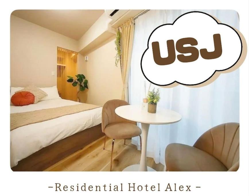 大阪701 Residential Hotel Alex USJまで1駅5分的一间设有一张床铺和一张桌子的房间,里面装有泡泡泡